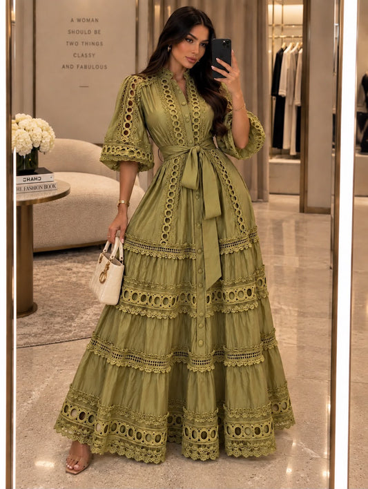 Woman wearing an olive green tiered maxi shirt dress with ornate cutout lace trim and a tie waist
